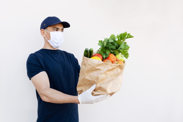 Food delivery during corona virus outbreak. Courier wearing face mask delivering grocery order in coronavirus epidemic. Safe shopping in pandemic. Takeout meal. People stockpile food.