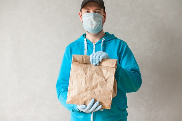 Food delivery courier is holding a large paper bag in his hands