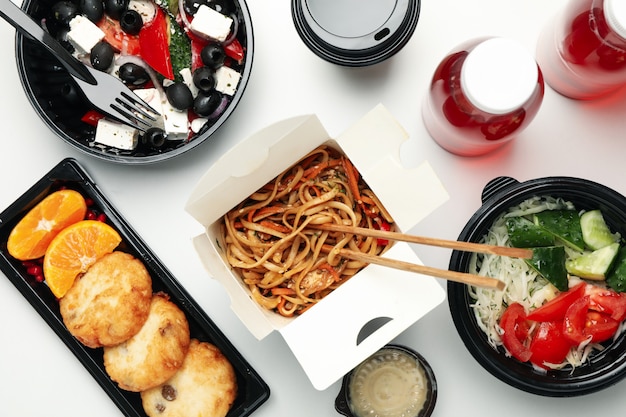 Food delivery. Food in takeaway boxes on white wall