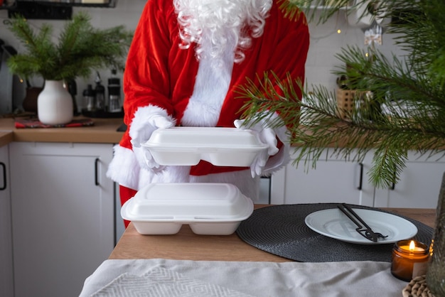 Food delivery to home service containers in hands of Santa Claus puts it on kitchen table and takes it away Readymade hot order Christmas New year holidays catering