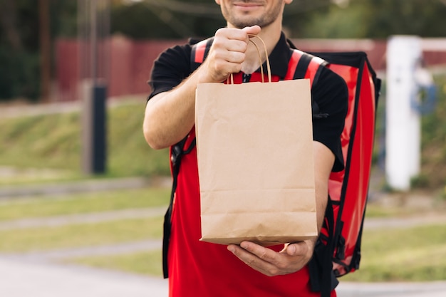 Фото Доставщик еды заказывает из ресторана красивый молодой человек в футболке и кепке счастливая доставка