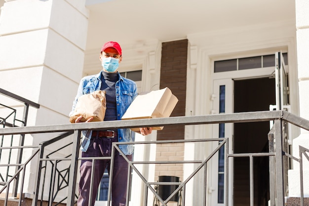 food delivery man with bags in a protective mask on his face