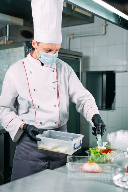 Food delivery in the restaurant. The chef prepares food in the restaurant and packs it in disposable dishes.