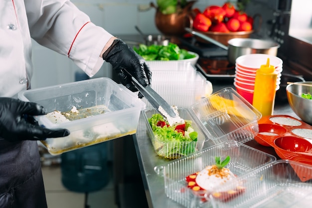 Food delivery in the restaurant. The chef prepares food in the restaurant and packs it in disposable dishes.