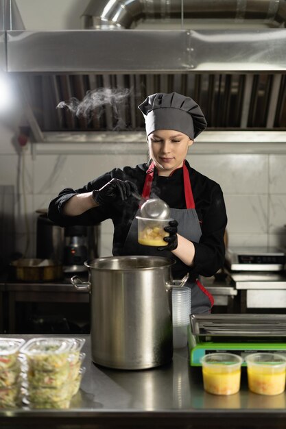 Food delivery to the restaurant the chef prepares food in the restaurant and prepares it in disposable plastic utensils pours soup into the lunch box and weighs the required portion on the scales