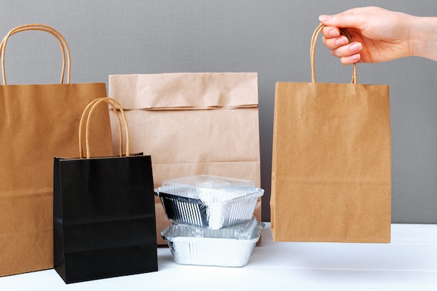 Food delivery service. brown craft paper bag package in female hand. delivery mock up packaging.