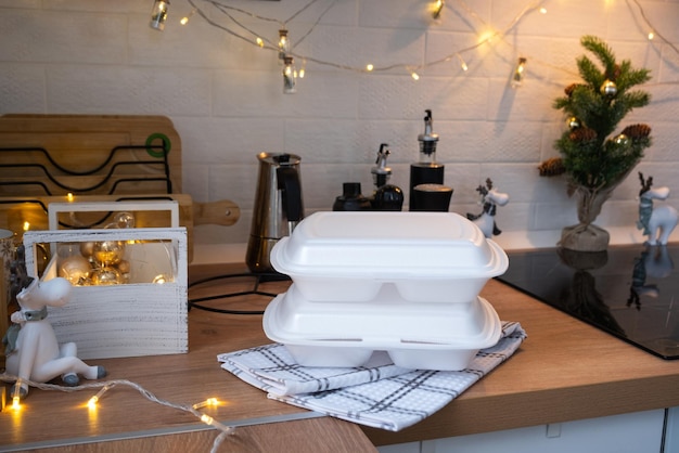 Food delivery service containers on table white scandi festive kitchen in christmas decor Eve New year saving time too lazy to cook hot order disposable plastic box in fairy light mock up