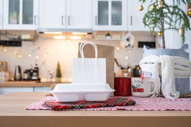 Food delivery service containers on table white scandi festive kitchen in christmas decor Eve New year saving time too lazy to cook hot order disposable plastic box in fairy light mock up