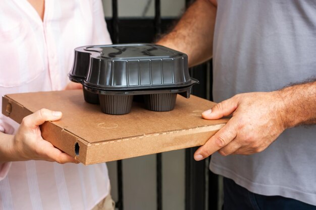 Foto uomo del servizio di consegna cibo con cartone per pizza e tazze da caffè da asporto che consegnano cibo al cliente