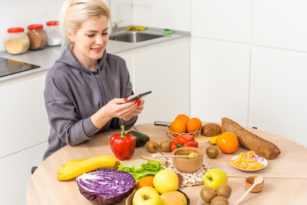 Servizio di consegna cibo - donna che tiene smartphone davanti alla consegna di cibo sano di verdure.