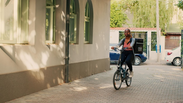 Food delivery service worker carrying backpack on bike, working as carrier to give takeaway meals to people. Woman riding bicycle and delivering restaurant food orders in packages.