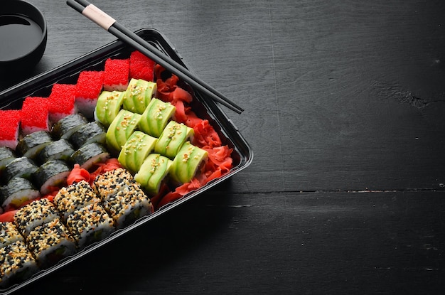 Food delivery sushi rolls Set of sushi in a plastic box Japanese Traditional Cuisine Top view Rustic style