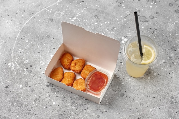 Food delivery, takeaway food in paper containers with hot\
chicken nuggets and refreshment drink lemonade in plastic glass.\
menu and logo mockup