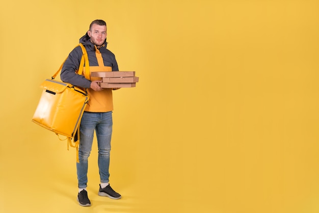 Food delivery young man in a yellow jacket