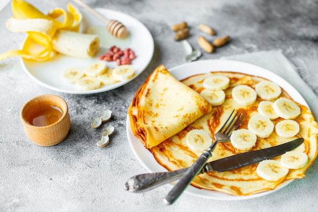 Food, dessert, pastries, pancake, pie. Tasty beautiful pancakes with banana and honey on a concrete background