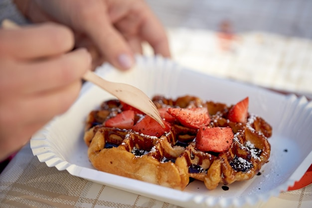 食べ物、デザート、人のコンセプト – イチゴとワッフルを食べる女性の接写