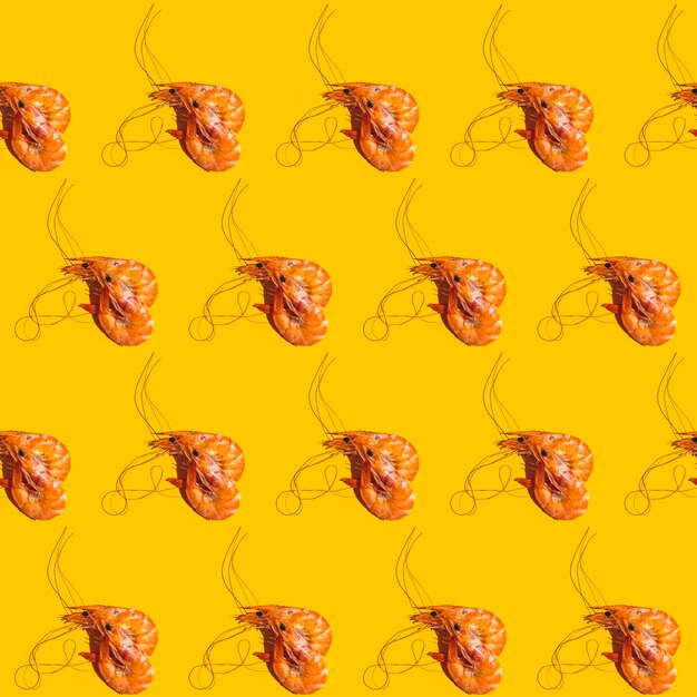 Food diagonal seamless pattern of shrimps on bright yellow background Creative minimalist flat lay with hard light