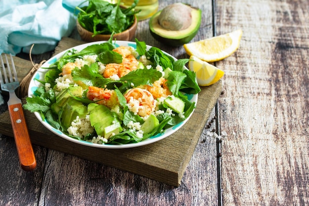 Food dieting concept Couscous salad with arugula avocado and grilled shrimps Copy space