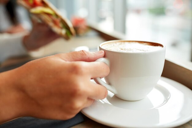 写真 食事夕食人々のコンセプト - カフェでコーヒーを飲みパニニサンドイッチを朝食や昼食に食べる女性