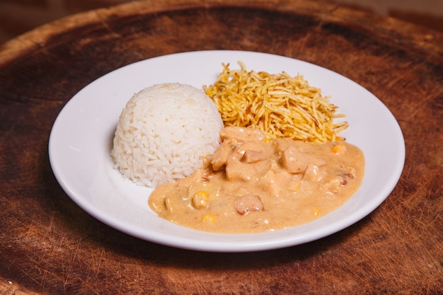 Food dish with chicken stroganoff and rice and chips