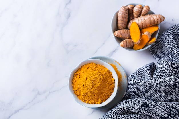 Photo food and drink, diet nutrition, health care concept. raw organic orange turmeric root and powder, curcuma longa on a cooking table. indian oriental low cholesterol spices. copy space background