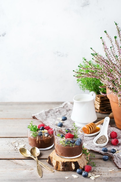 Food and drink healthy eating and dieting concept Homemade chocolate chia pudding with fresh berries and green thyme for breakfast on a cozy kitchen wooden table Copy space background