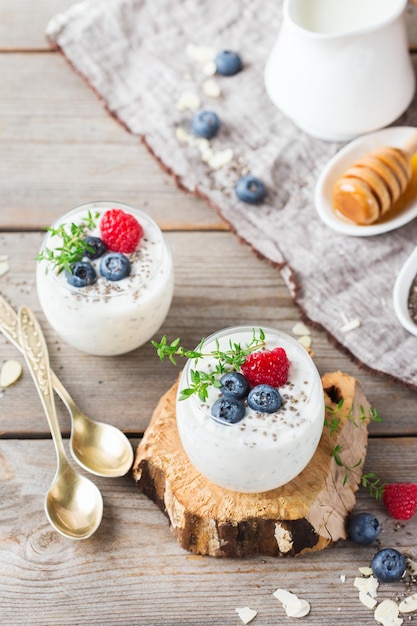 Food and drink healthy eating and dieting concept Homemade white chia pudding with fresh berries and green thyme for breakfast on a cozy kitchen wooden table