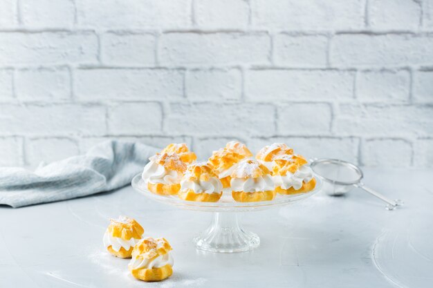 Food and drink, holidays concept. Delicious sweet homemade profiteroles with cream on a modern kitchen table. Copy space background