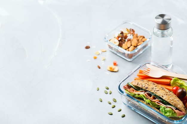 Cibo e bevande, natura morta, dieta e nutrizione, alimentazione sana, concetto da asporto. lunch box con sandwich, frutta, verdura, mix di noci e bottiglia d'acqua. copia lo sfondo dello spazio