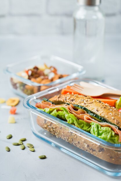 Food and drink, still life, diet and nutrition, healthy eating, take away concept. Lunch box with sandwich, fruits, vegetables, nut mix and bottle of water