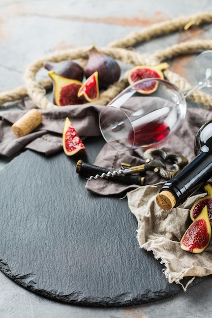 Food and drink still life holidays seasonal harvesting fall autumn concept Bottle corkscrew corks glass of red wine and figs on a grunge table Copy space background