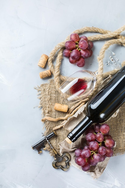 Food and drink still life holidays seasonal harvesting fall concept Bottle corkscrew corks glass of red wine and grapes on a trendy concrete table Copy space background top view flat lay