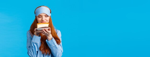 食べ物を食べることとデザートのコンセプト ナイトウェア睡眠マスクで陽気なかなり赤毛の女性 sm を閉じます