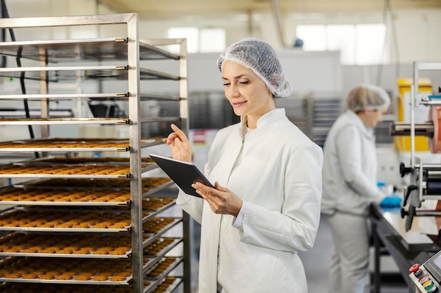 Супервайзер пищевой фабрики проверяет качество печенья на предприятии.