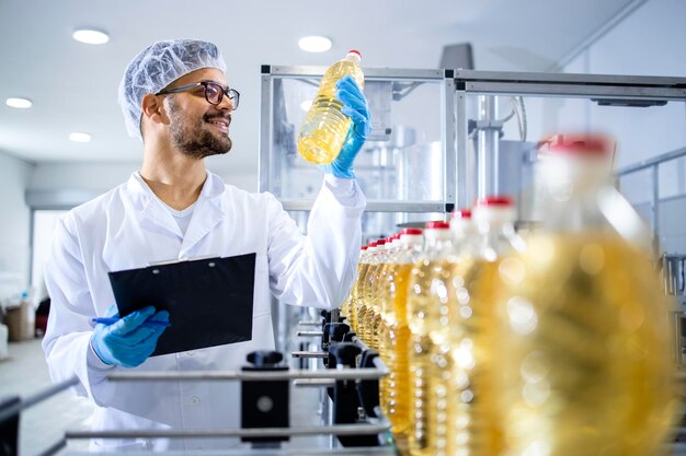 Food factory technologist holding bottle of vegetable oil and checking quality