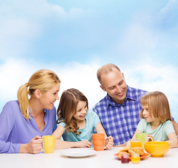 食べ物、家族、子供、幸福と人々の概念-家で朝食をとっている2人の子供を持つ幸せな家族