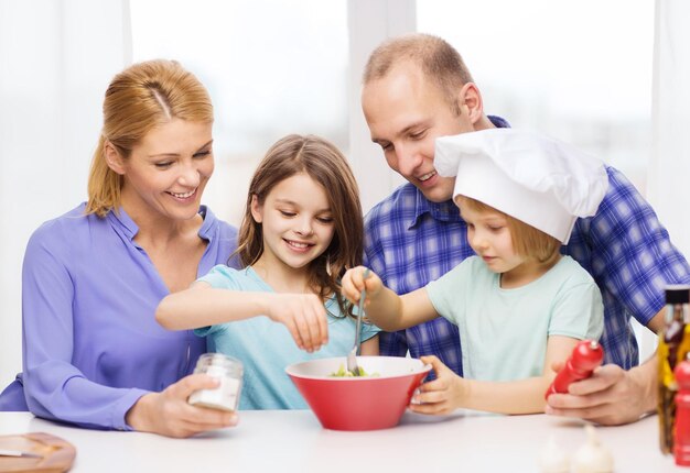 食べ物、家族、子供、幸福と人々の概念-家で夕食を作る2人の子供を持つ幸せな家族