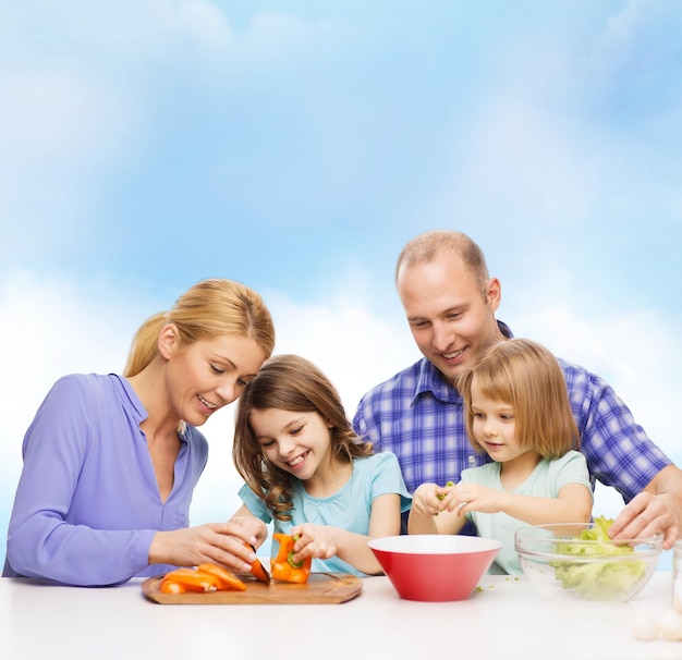 食べ物、家族、子供、幸福と人々の概念-家で夕食を作る2人の子供を持つ幸せな家族