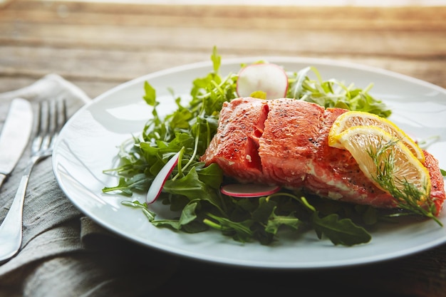 food fish protein and salad with nutrition for wellness lunch plate and lose weight with pescatarian diet salmon rocket and plant leaves or herbs for gut health with fine dining on wood table