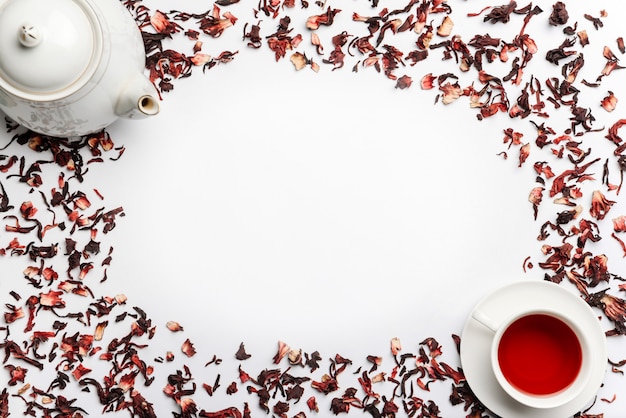 ハイビスカスティー、ティーポット、白い壁に分離された紅茶のカップの鋳造からのフードフレーム