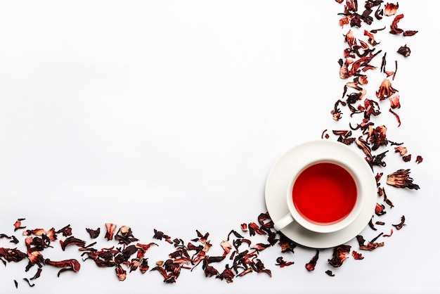 Photo food frame with cup and petal of hibiscus tea isolated on white wall with space for text.