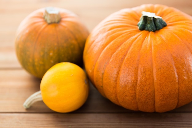 food, harvest, season and autumn concept - close up of pumpkins on wooden table at home