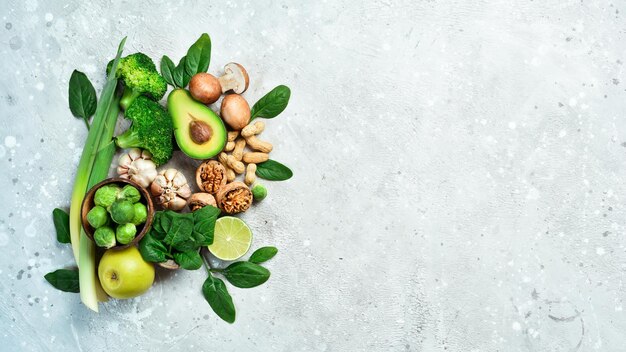 Food for heart health Green vegetables fruits nuts and mushrooms On a gray stone background Top view