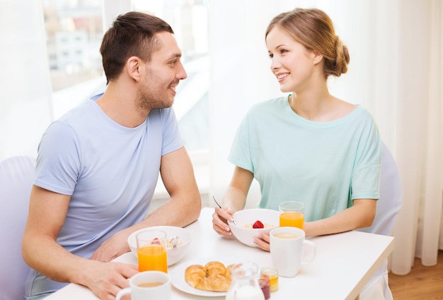 food, home, couple and happiness concept - smiling couple having breakfast at home