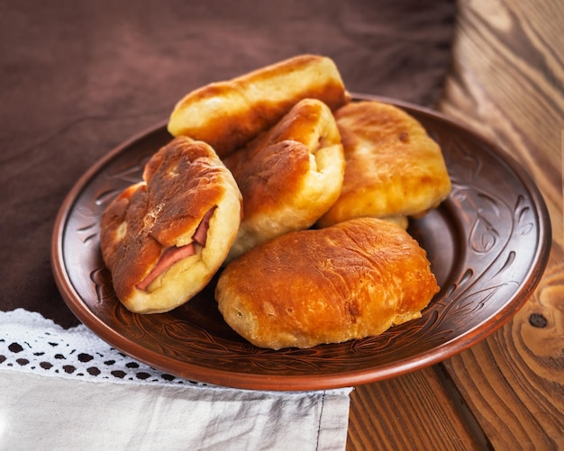 Food at home pies with sausages on a ceramic brown plate close-up cotton napkin