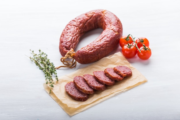 Еда, конина и вкусная концепция - вид сверху нарезанной колбасы с помидорами и перцем.
