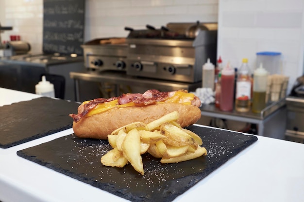 FOOD hot dog with mustard grilled bacon and fried potatoes in a restaurant