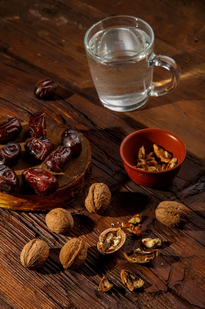 Cibo per iftar durante il digiuno del ramadan datteri noci e acqua, sul tavolo. foto verticale