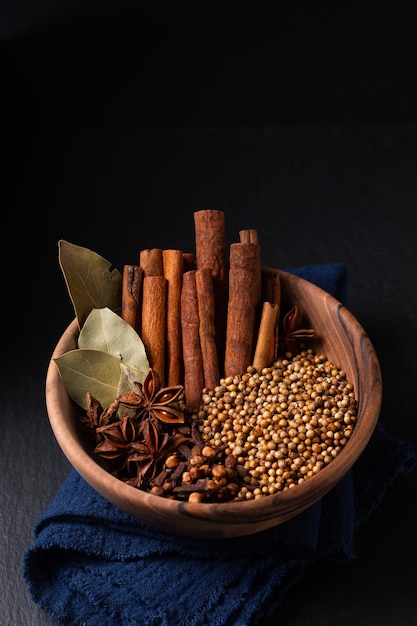 Пищевой ингредиент Thai Five Spice в деревянной миске на черной сланцевой каменной доске с копией пространства