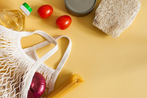 Photo food items in a string bag on a yellow surface with space for text